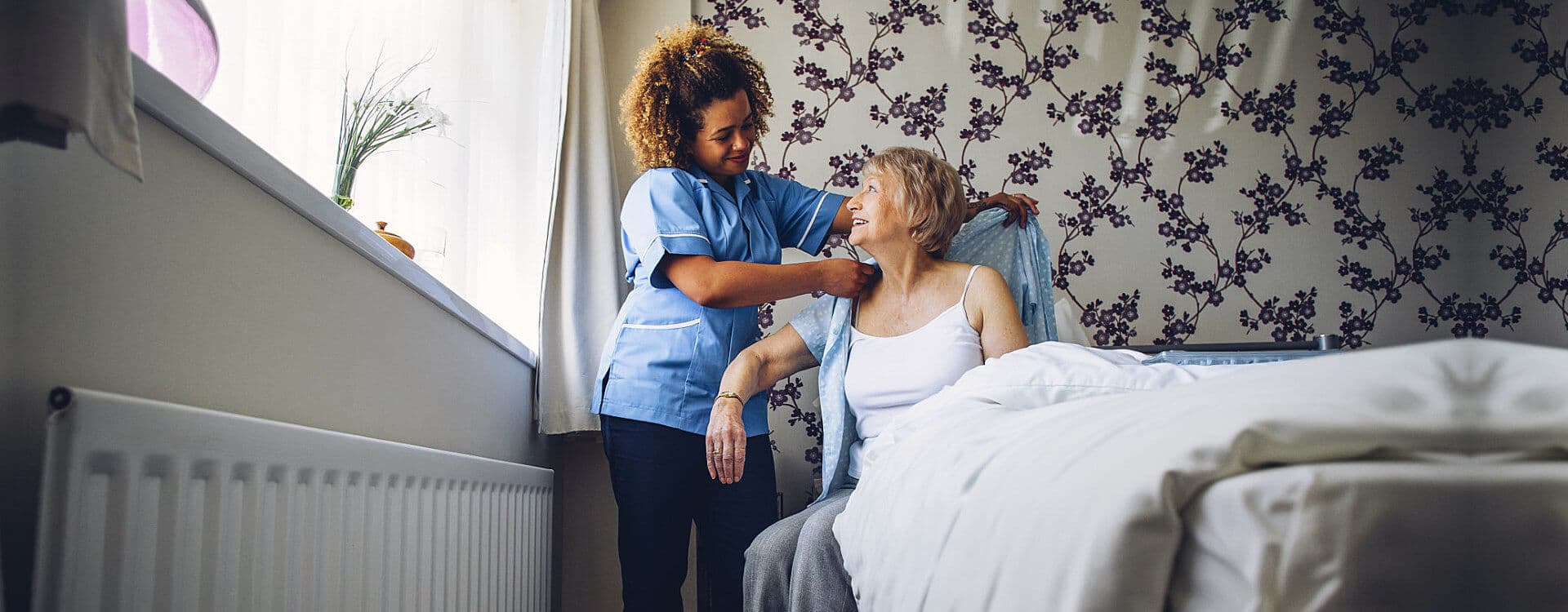 caregiver assisting patient in wearing her clothes
