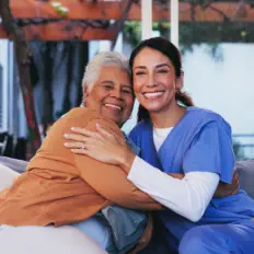 caregiver and an elderly smiling and hugging