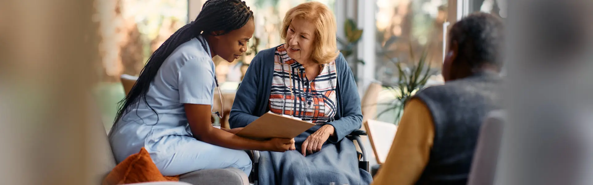a nurse talks with an elderly woman while reviewing a clipboard